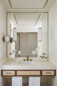 La salle de bains est pourvue d'un lavabo et d'un grand miroir. dans l'établissement Hotel La Palma Capri, an Oetker Collection Hotel, à Capri