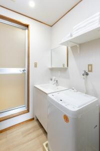 a white bathroom with a sink and a window at Chikyuutabikazoku　Kintetsu-Nara Ekimae in Nara