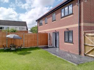 a patio with a table and an umbrella next to a brick building at Modern Spacious 4 Bed House-with Private Parking in Birmingham 
