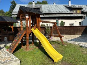 a playground with a yellow slide in a yard at Casa Maramureșană in Vişeu de Sus