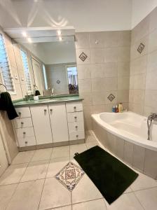 een badkamer met een bad, een wastafel en een spiegel bij Neve Tsedek Rooftop in Tel Aviv