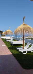a row of lawn chairs with umbrellas and the ocean at Apartment Island Paradise in Adeje