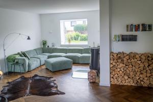 een woonkamer met een bank en een stapel hout bij Eifel21 - stilvolles Haus in der Vulkaneifel in Bleckhausen