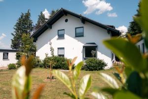 een wit huis met een zwart dak bij Eifel21 - stilvolles Haus in der Vulkaneifel in Bleckhausen