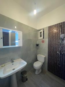 ein Bad mit einem Waschbecken, einem WC und einer Dusche in der Unterkunft Miranda's Apartments & Rooms in Sarandë