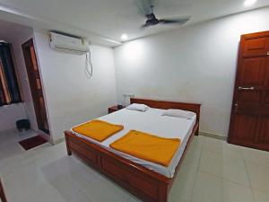 a bedroom with a bed with orange sheets and a fan at STAYMAKER Shri Shakti Residency in Hubli
