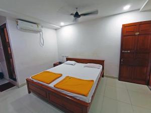 a bedroom with a bed with orange sheets and a fan at STAYMAKER Shri Shakti Residency in Hubli
