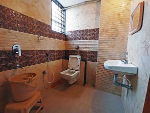 a bathroom with a toilet and a sink in it at STAYMAKER Shri Shakti Residency in Hubli