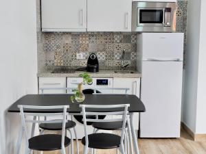 uma cozinha com uma mesa e cadeiras pretas e um frigorífico em Apartamentos cruz roja B em Sevilha