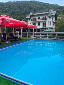 a large swimming pool with a red umbrella and a building at River View in Lohovo