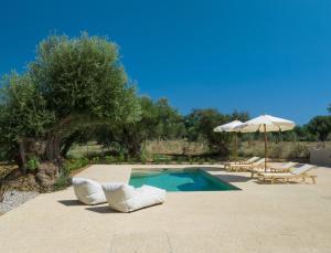 a swimming pool with two lounge chairs and an umbrella at Terra Oleana Cottages in Vasilikos