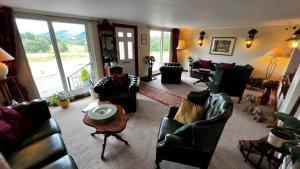 a living room with leather furniture and a large window at Springburn Farmhouse in Spean Bridge