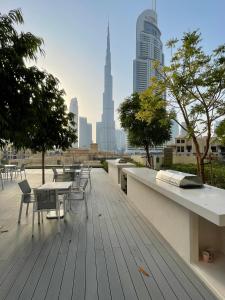 eine Holzterrasse mit Tischen und Stühlen auf einem Gebäude in der Unterkunft Luxurious one-bedroom very close to Dubai Mall in Dubai