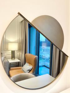 a circular mirror in a hotel room with a chair and a window at Luxurious one-bedroom very close to Dubai Mall in Dubai