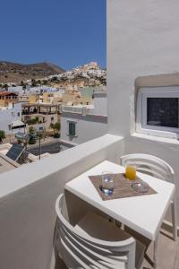 a white table with a glass of orange juice on a balcony at Vivianna’s guest house in Ermoupoli