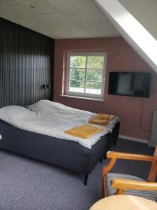 a bedroom with a bed and a flat screen tv at Kristinebjerg in Jelling