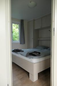 a bedroom with a large bed with a window at Minicamping In de Bocht in Grijpskerke