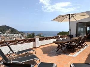 een patio met een tafel en stoelen en een parasol bij LETS HOLIDAYS Beautiful house sea views in Tossa de Mar