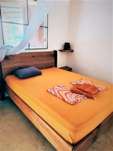 1 cama grande con sábanas de color naranja y ventana en Terra NaturaMa - off grid living in the jungle, en Punta Uva