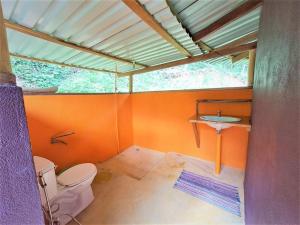an orange bathroom with a toilet and a sink at Terra NaturaMa - off grid living in the jungle in Punta Uva