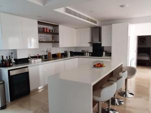 a kitchen with white cabinets and a counter with chairs at The Family Nest Villa in Cyprus in Paphos