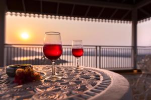 dos vasos de vino tinto sentados en una mesa en Lake Arches by StayVista - Lakeside villa with Infinity pool, Gazebo & Modern Greek interiors, en Igatpuri