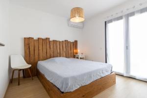 a bedroom with a bed with a wooden headboard at PÉ NA AREIA II by Stay in Alentejo in Vila Nova de Milfontes