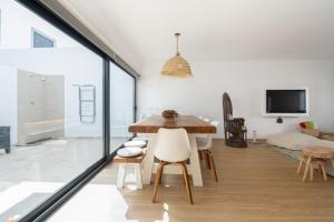 a dining room with white walls and a table and chairs at PÉ NA AREIA II by Stay in Alentejo in Vila Nova de Milfontes