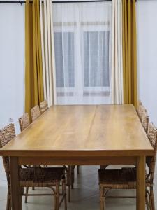 a wooden table with chairs in a room with a window at Appartments Meuble SEED in Yaoundé