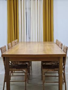 a wooden table with chairs and curtains in a room at Appartments Meuble SEED in Yaoundé