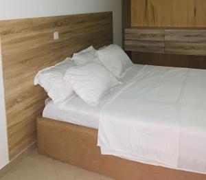 a bed with white sheets and pillows in a room at Appartments Meuble SEED in Yaoundé