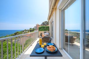 una mesa con comida en un balcón con vistas al océano en Proche Monaco, vue mer et accès à la plage, en Saint-Antoine