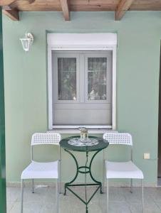 una mesa y 2 sillas y una ventana en un patio en Lovely Guesthouse On The Beach en Ayia anna