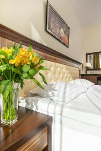 a vase of yellow flowers on a table next to a bed at Grand SPA Lietuva Hotel Lietuva in Druskininkai