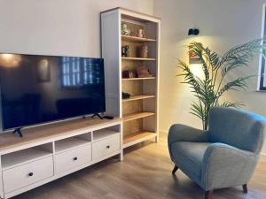 a living room with a television and a blue chair at Casa Senda de los Miradores in Muros de Nalón