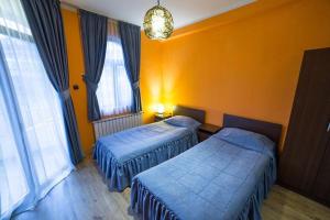 two beds in a room with orange walls and windows at Kris Hotel & Restaurant in Smolyan