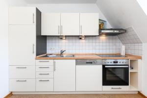 a kitchen with white cabinets and a sink at Ferienwohnung Inselblick in Bensersiel