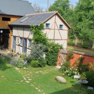 una pequeña casa blanca con un jardín delante de ella en Ankommen, Wohlfühlen und die Natur genießen en Lichtenhain