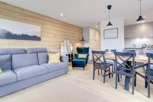uma sala de estar com um sofá, uma mesa e cadeiras em Le Major Apartment em Morzine