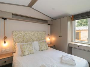 a bedroom with a white bed with pillows and a window at Lodge 11 in Winscombe
