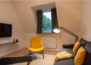 salon z kanapą i żółtym krzesłem w obiekcie Renoviertes Design Apartment mit Toller Terasse w mieście Mülheim an der Ruhr