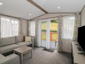 a living room with a couch and a balcony at Lodge 10 in Winscombe