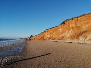 a sandy beach next to a brown cliff at Maison située entre plage la mine d'or et bourg in Pénestin