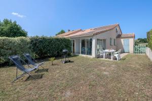 a yard with chairs and a grill and a house at Maison avec piscine à 200m de la plage in Saint-Michel-Chef-Chef