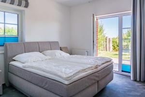 ein großes Bett in einem Zimmer mit einem großen Fenster in der Unterkunft Ferienhausanlage Sonne in Dranske