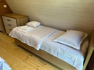 1 cama con sábanas blancas y almohadas en una habitación en Heart of Surami, en Surami