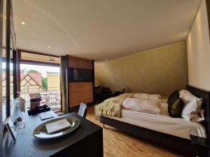 a bedroom with a bed and a table and a room with a balcony at Laurentius Boutique-Hotel & Restaurant in Weikersheim