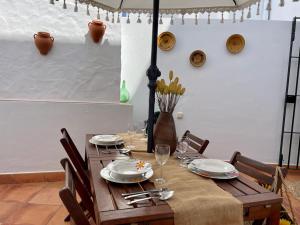a wooden table with chairs and plates and wine glasses at Apartamento Rubire in Vejer de la Frontera