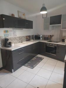 a kitchen with black cabinets and a white tile floor at Le Refuge in Saint-Aignan