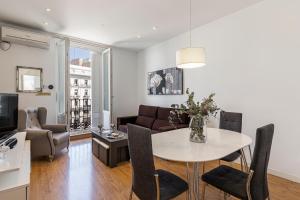 uma sala de estar com uma mesa e um sofá em BNBHolder Apartamentos en Sol Superior 1 em Madri